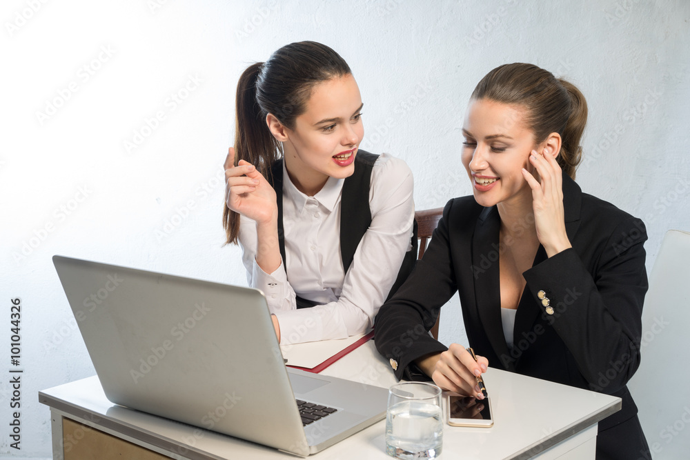 Two girls having fun in the office to discuss the working time of near laptop Two girls having fun in the office to discuss the working time of near laptop