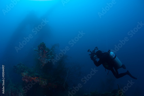 Underwater photographer exploring wreck ship in the deep.