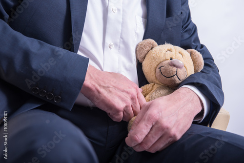 older man in suit snuggles with a stuffed animal .
blue suit . pedophile