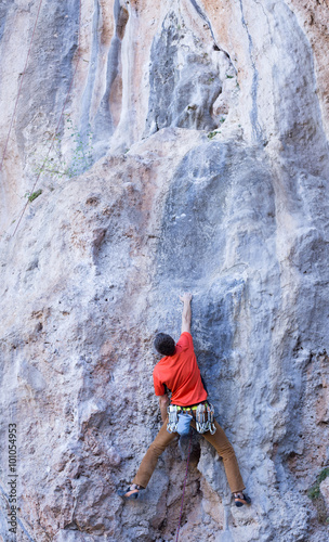 Young male climber hanging by a cliff