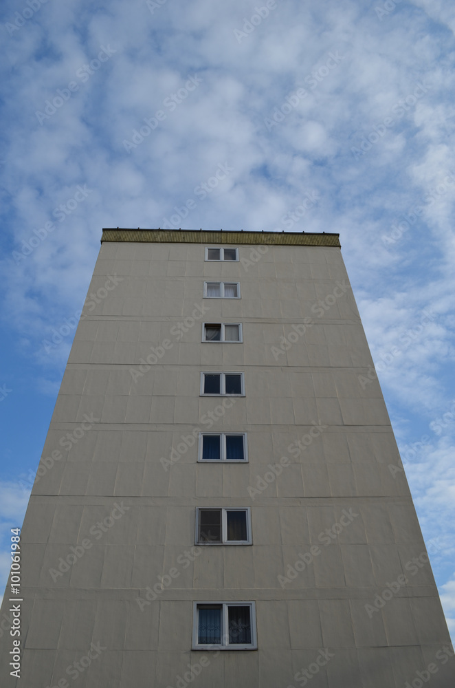 Yellow apartment building against blue sky with clouds Yellow apartment building against blue sky with clouds