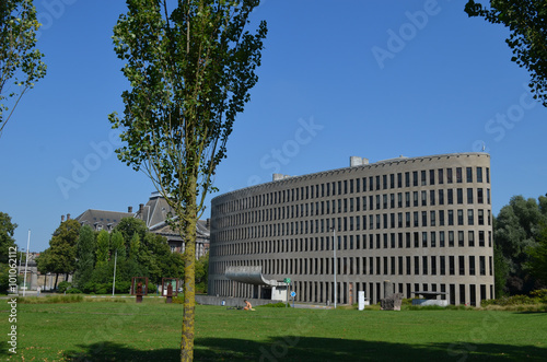 Green park with tall trees at the university of Brussels, with modern ellips formed building