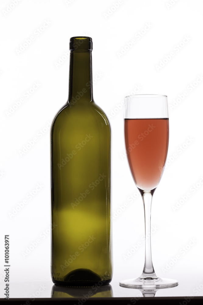 glass of pink wine and empty bottle on white background