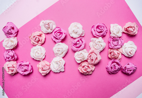 word love made of paper roses, decorations for Valentine's Day on paper white rustic background top view close up