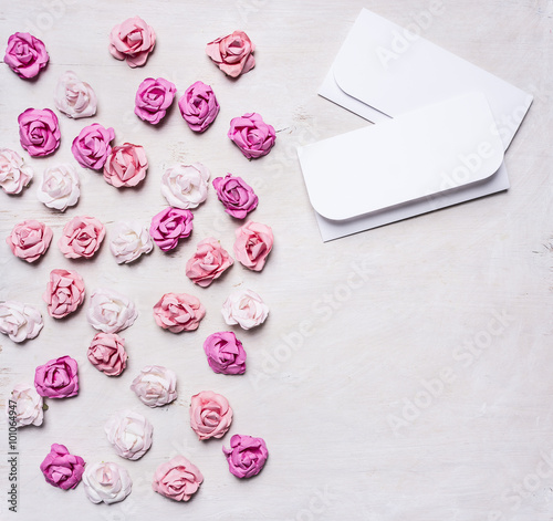 colorful paper roses with envelopes, Valentine's Day border ,with text area on white wooden rustic background top view close up