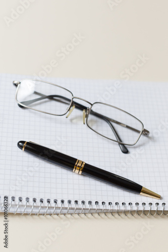 black pen and glasses with white pad or notepad