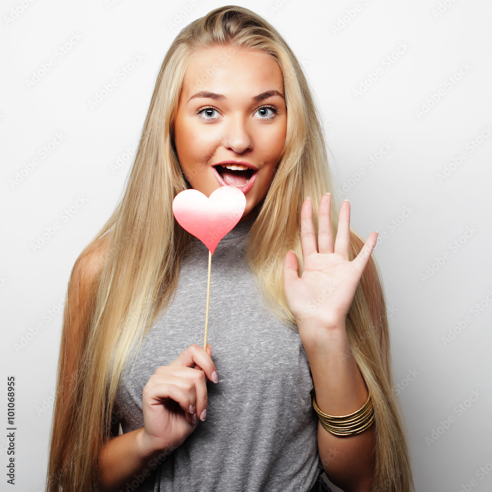 Playful young woman holding a party heart. Playful young woman holding a party heart.