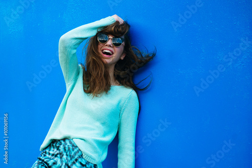 Portrait of cheerful girl on a blue background in sunglasses