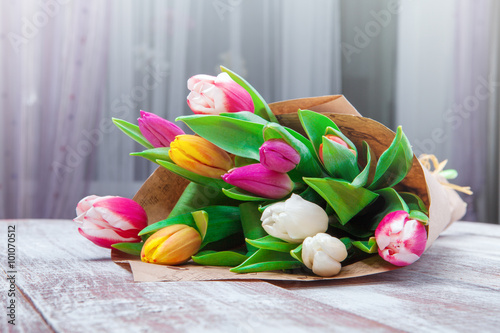 the bouquet of tulips is wrapped in a paper isolated on a wood b #101070512