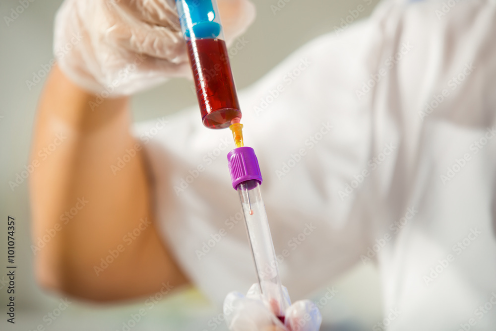 Close up of a protected scientist dropping liquid in a test tube in a laboratory Close up of a protected scientist dropping liquid in a test tube in a laboratory