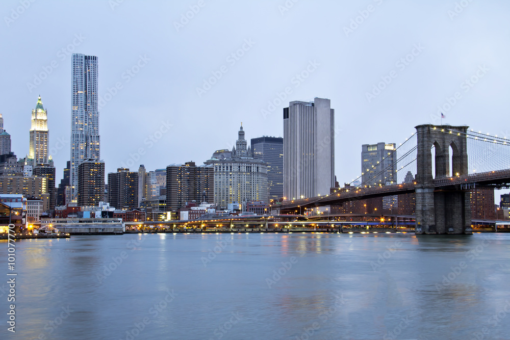 New York City Brooklyn Bridge and Manhattan skyline with skyscrapers over Hudson River at dusk after sunset. New York City Brooklyn Bridge and Manhattan skyline with skyscrapers over Hudson River at dusk after sunset.