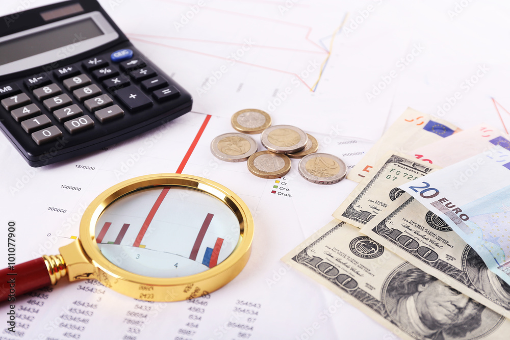 A magnifying glass on financial documents background, close-up A magnifying glass on financial documents background, close-up