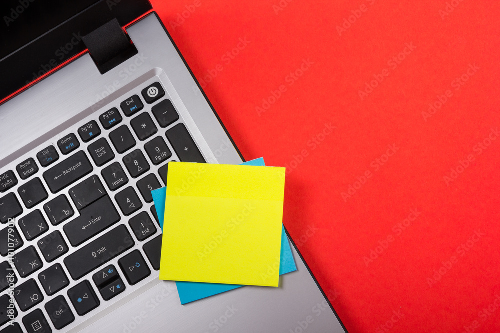Office table desk with set of colorful supplies, white blank note pad, cup, pen, pc, crumpled paper, flower on red background. Top view and copy space for text Office table desk with set of colorful supplies, white blank note pad, cup, pen, pc, crumpled paper, flower on red background. Top view and copy space for text