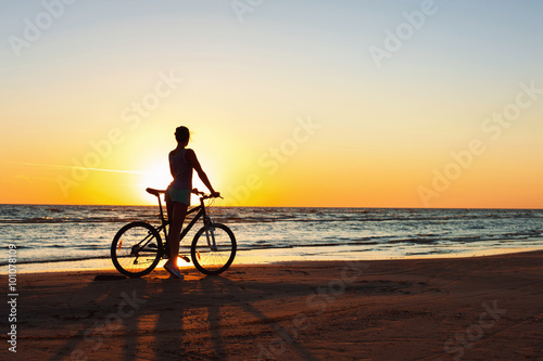 Catching a moment in time. Sporty woman cyclist at sunset backgr