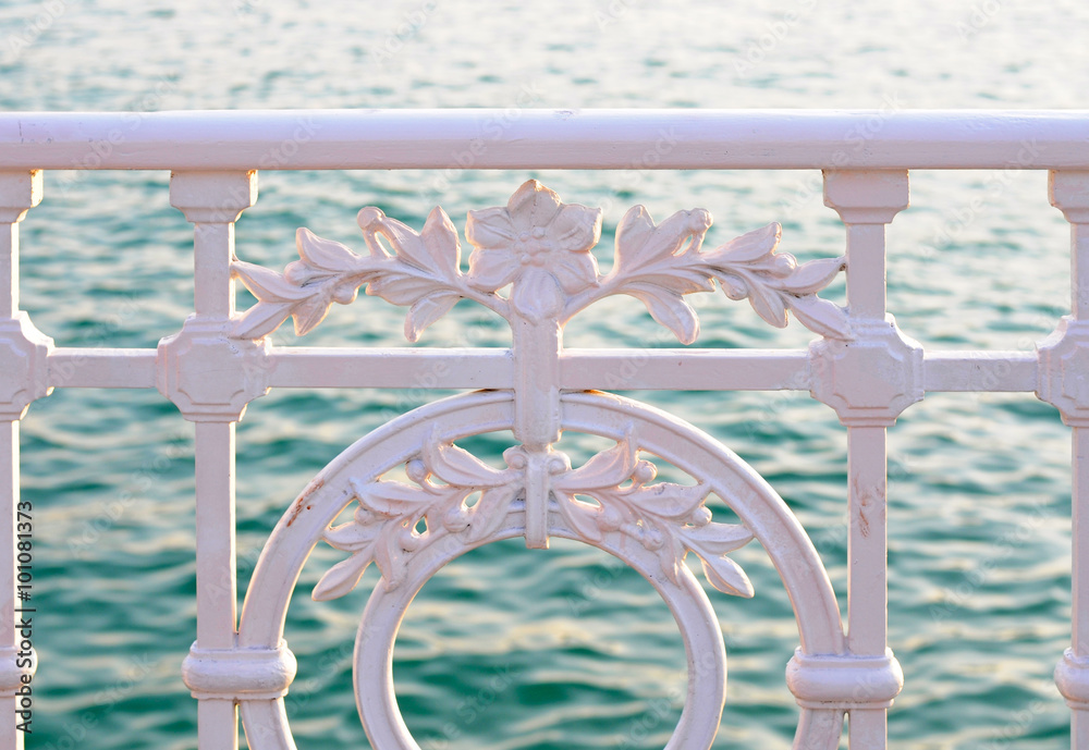 weathered wrought iron fence with flower pattern in front of the sea, selective focus weathered wrought iron fence with flower pattern in front of the sea, selective focus