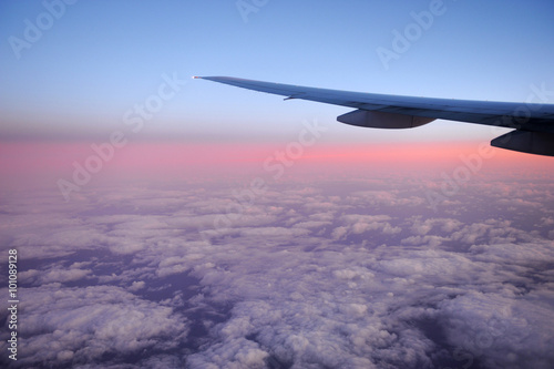 pink dawn light on the cloud under the airplane wing
