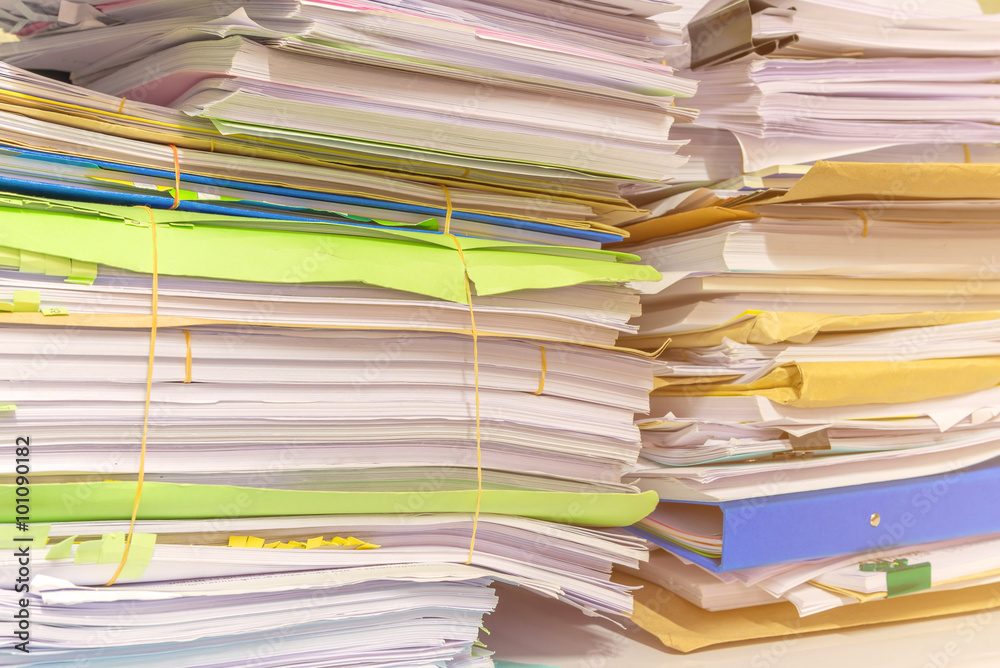 Pile of documents on desk stack up high waiting to be managed Pile of documents on desk stack up high waiting to be managed
