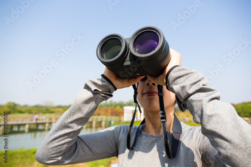 Woman looking though binocular for bird watching