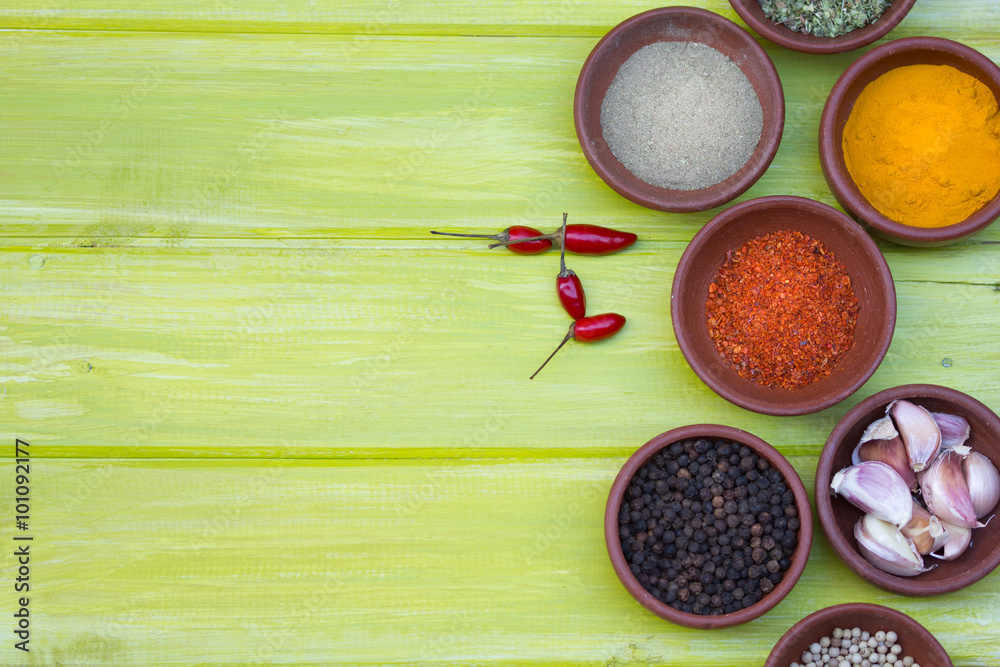 Dry colorful spices in clay bowls on green wooden background, top view Dry colorful spices in clay bowls on green wooden background, top view