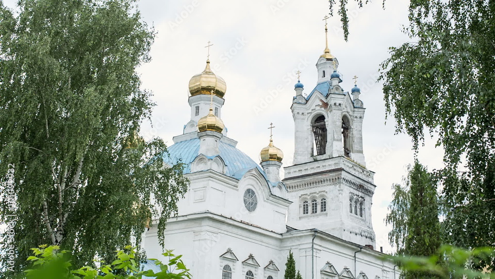 Russian Christian temple or church. The old white building with a golden dome.It cuts through the leaves and bushes. Russian soul and the Russian history Russian Christian temple or church. The old white building with a golden dome.It cuts through the leaves and bushes. Russian soul and the Russian history