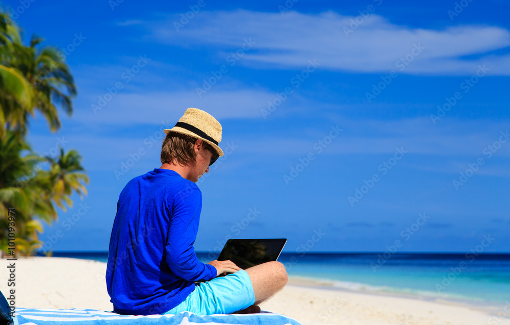 man with laptop on tropical beach