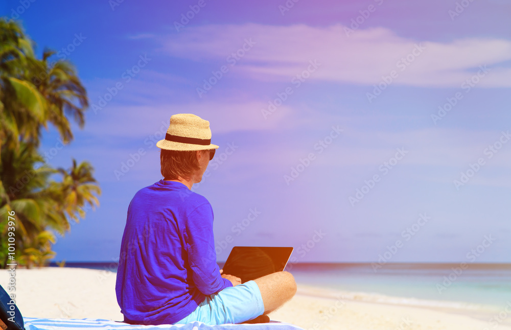 man with laptop on tropical beach