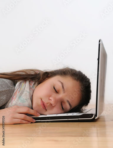 beautiful young woman asleep on her laptop against a white backg