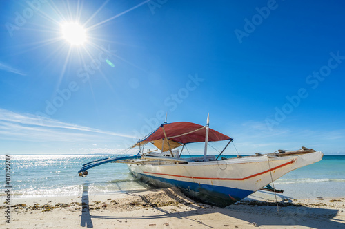 Philippines traditional fishing boat in the clear sea waters on Bantayan island on the blue sky background with shining sun. Wide angle shoot. 