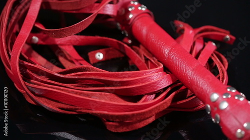 red leather whip for BDSM games. on a black background. sex toy
