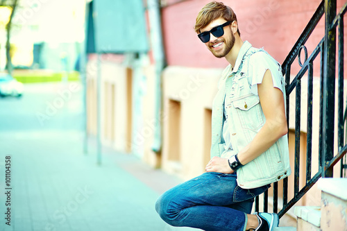 Funny smiling hipster handsome man guy in stylish summer clothes walking in the street posing in sunglasses