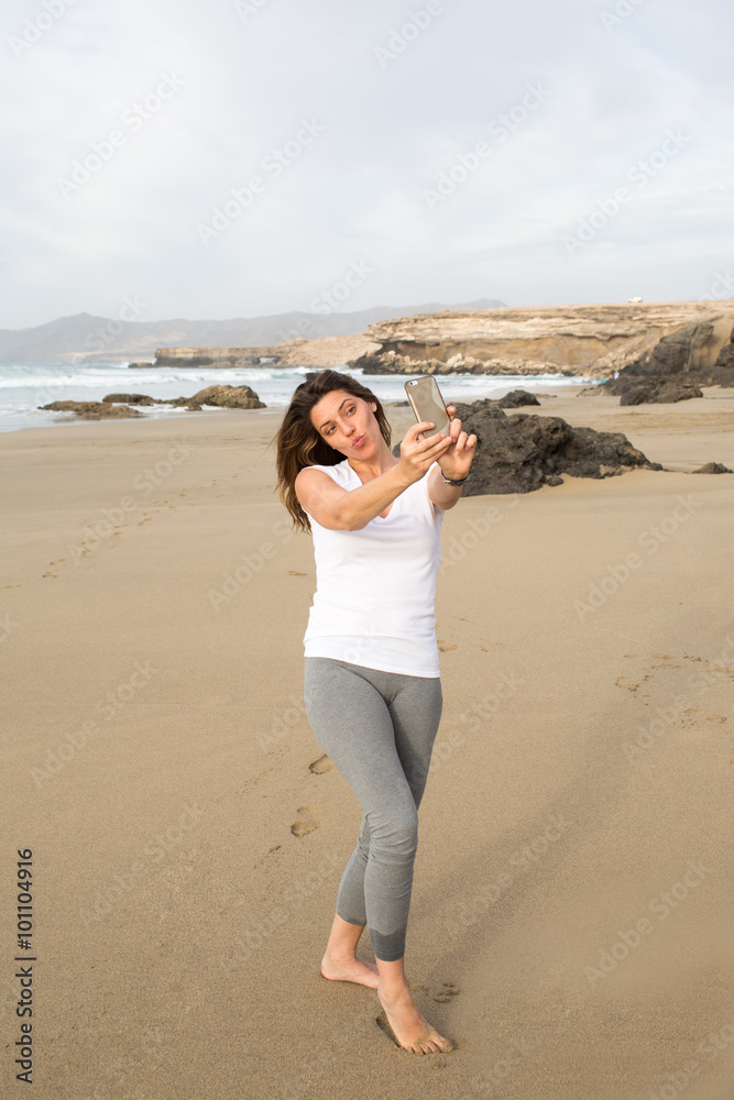 Huebsche Frau am Strand macht einen Selfie