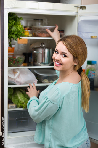  long-haired woman arranging space in fridge at home