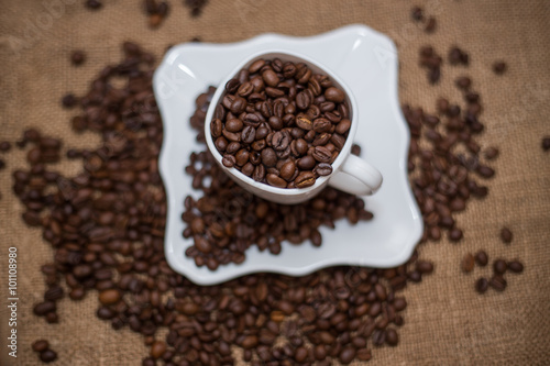 a scattering of coffee beans white cup and saucer on a table brown texture units large lot of grain