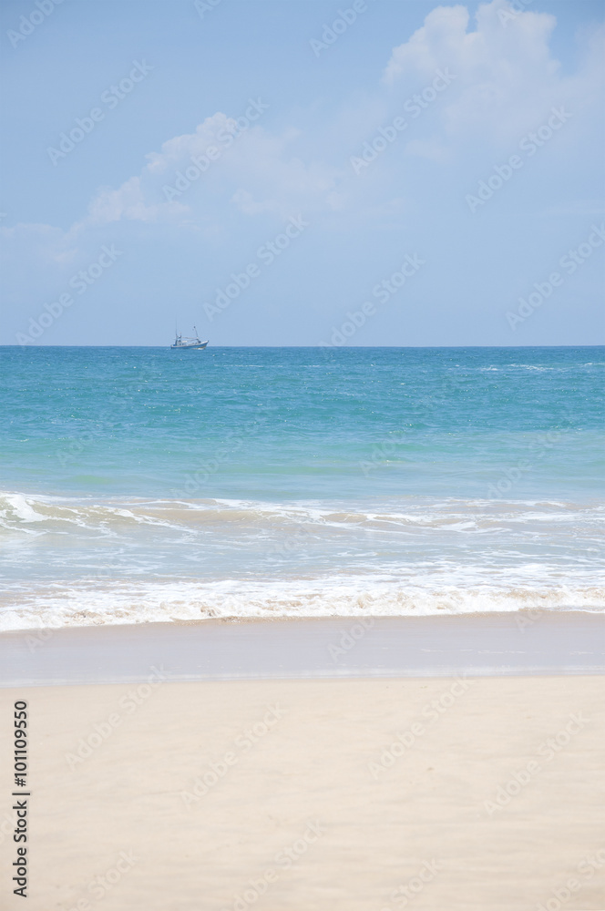 A boat sailing in the clear blue waters of the Indian Ocean on a bright sunny day in Sri Lanka