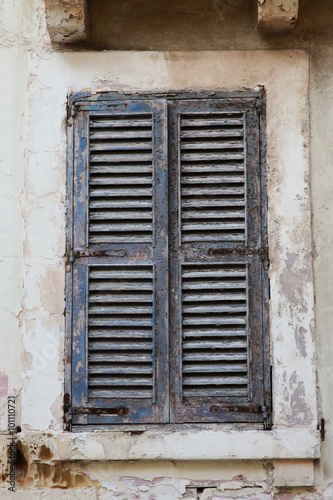 Blue peeling closed shuttered window