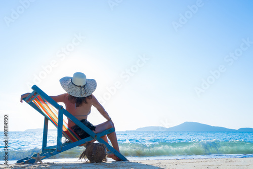 Woman sitting on the lounge chair at the beach © Netfalls