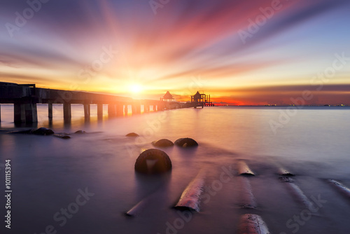 Landscape of wooden bridge extended into the sea at sunset.