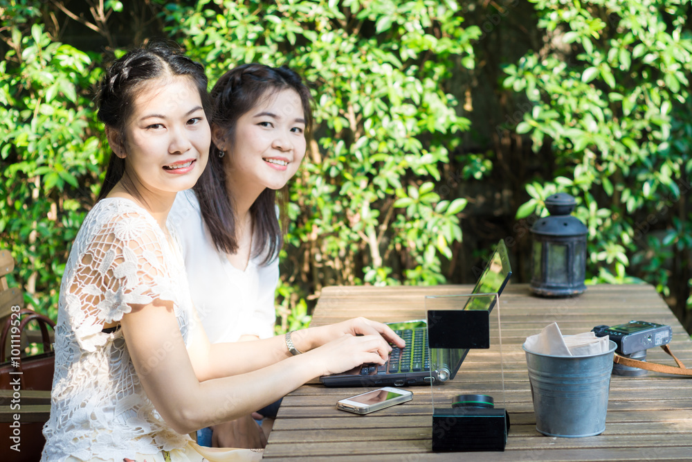 Two asian young female friends use internet together