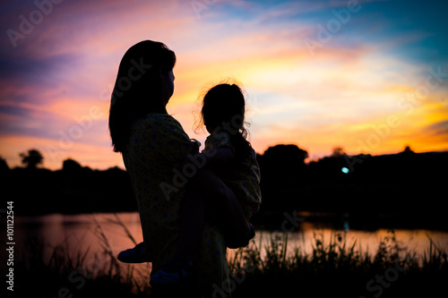Shadow of Mother holding her daughter to see the sunset silhouet