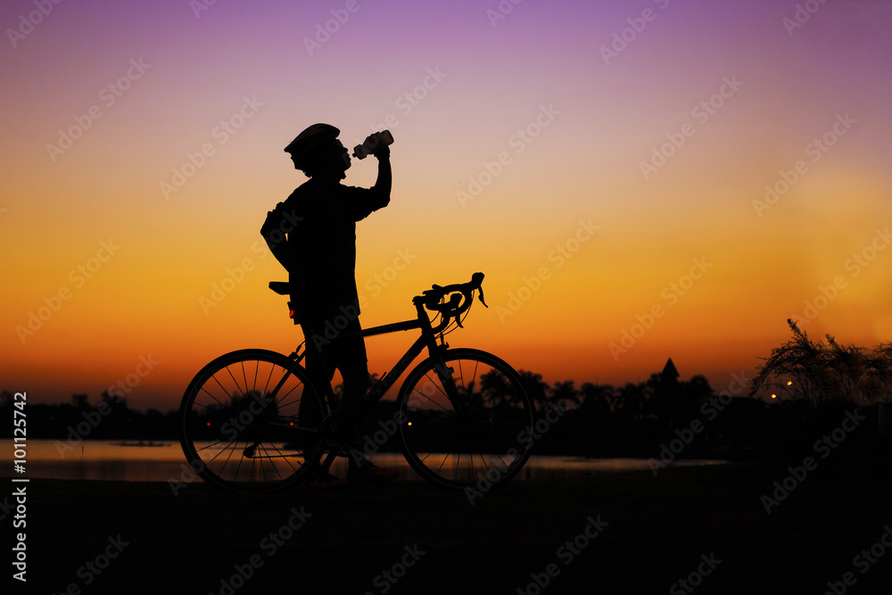 Obraz premium silhuette mountain bicycle rider drinking water at lake side aga