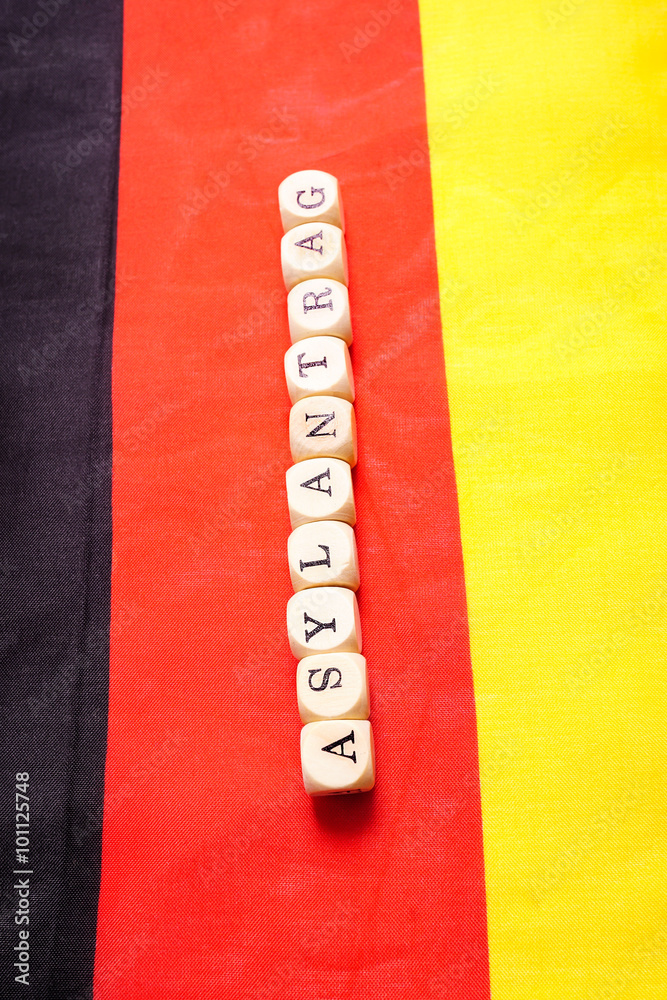 Asylantrag, Buchstabenwürfel auf Deutschlandfahne StockFoto Adobe Stock