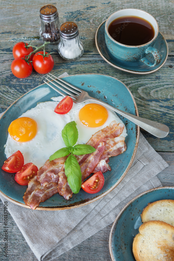 Fried eggs, bacon, tomato, toast and a cup of coffee Fried eggs, bacon, tomato, toast and a cup of coffee