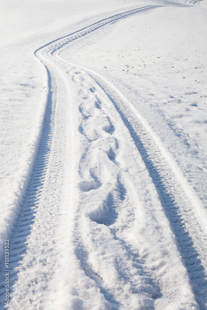 Car tire track and footprints on winter road Car tire track and footprints on winter road