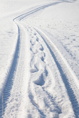 Car tire track and footprints on winter road © Radomir Rezny