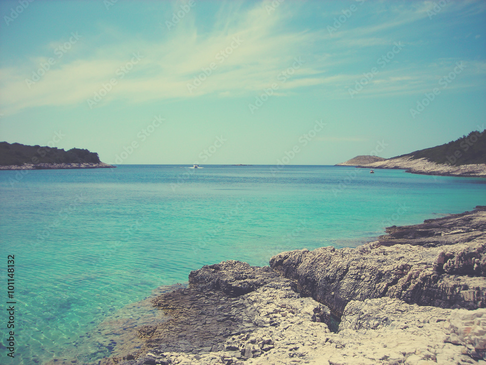 White rocky beach and clear blue sea on a sunny summer day. Image filtered in faded, retro, Instagram style with extremely soft focus; nostalgic, vintage concept of summer travel and holidays.