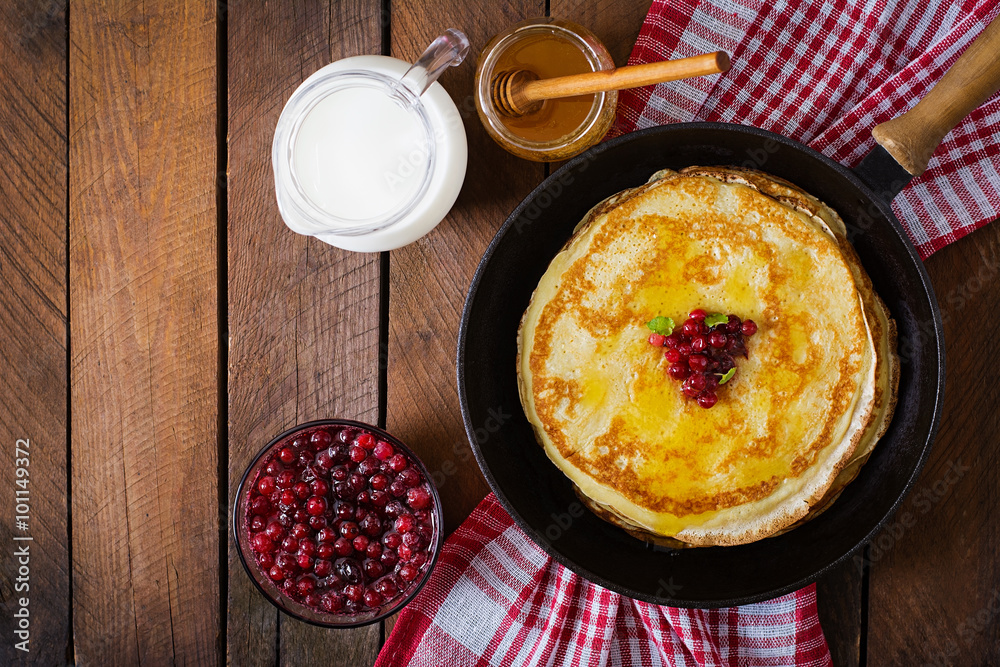 Golden pancakes with cranberry jam and honey in a rustic style. Top view Golden pancakes with cranberry jam and honey in a rustic style. Top view