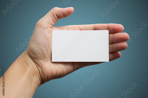 Hand holding white blank business visit card, gift, ticket, pass, present isolated on blue background. Copy space for text. Corporate identity package Template ID