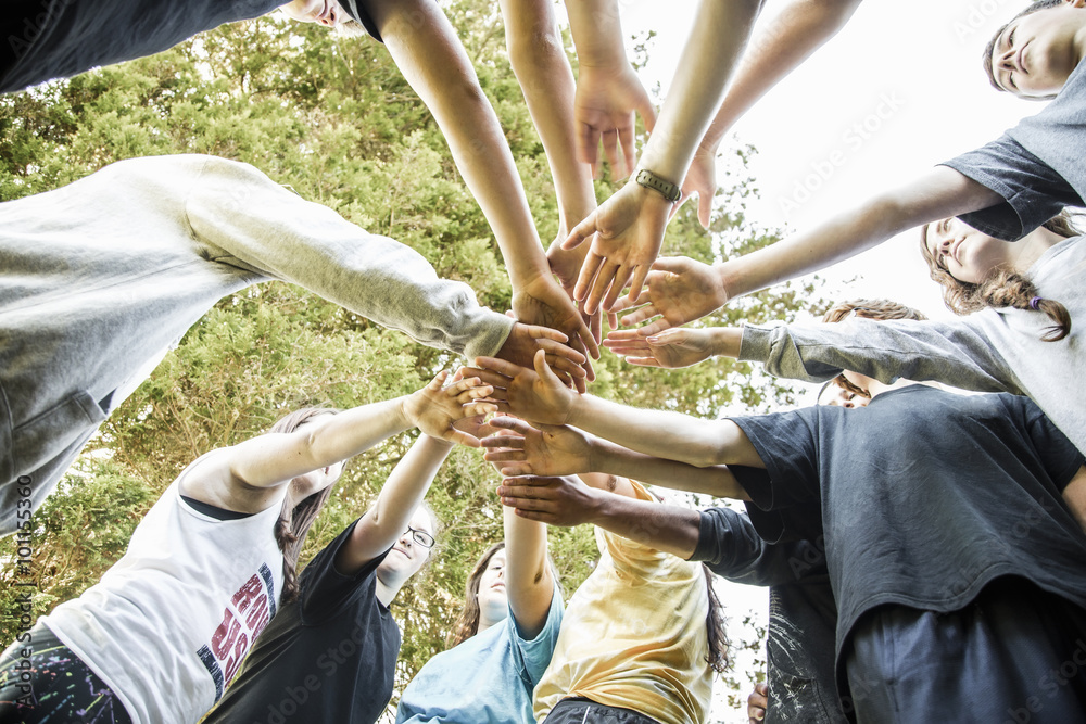 Caucasian teenagers putting hands together in huddle Caucasian teenagers putting hands together in huddle