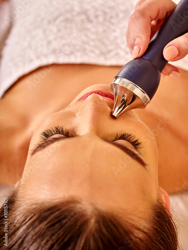 Woman receiving electric ultrusound facial massage at  hardware cosmetology beauty salon. 