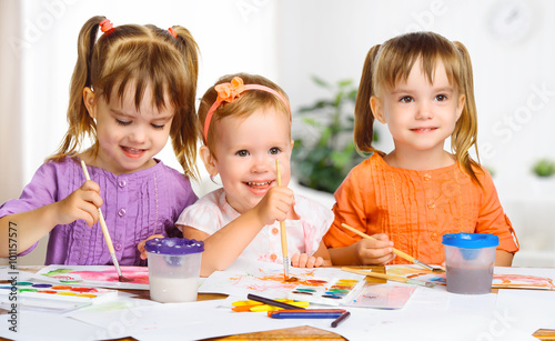 happy little girls in kindergarten draw paints